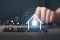 Das Bild zeigt eine Person, die auf ein Smartphone tippt und aufleuchtende Symbole für Energiemanagementsystem eines Hauses.